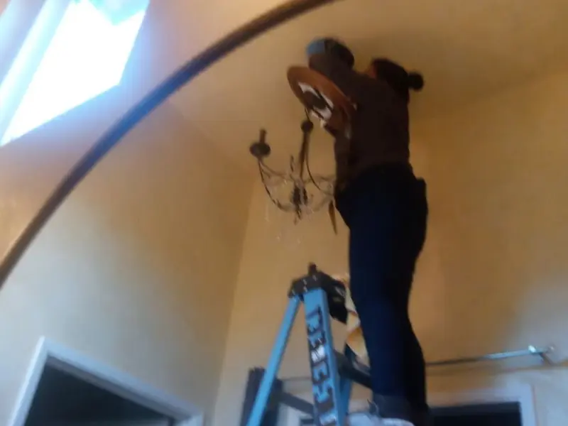 Electrician installing a chandelier in a Carlsbad residence